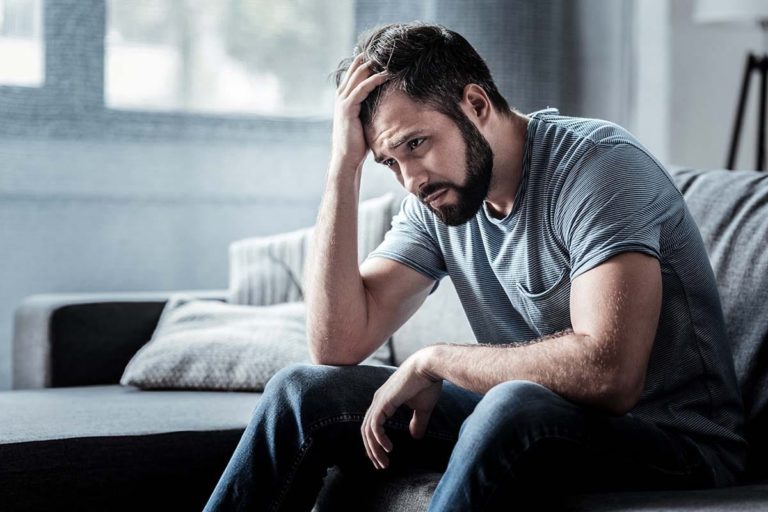 man sitting on bed dealing with mental health and substance abuse laws