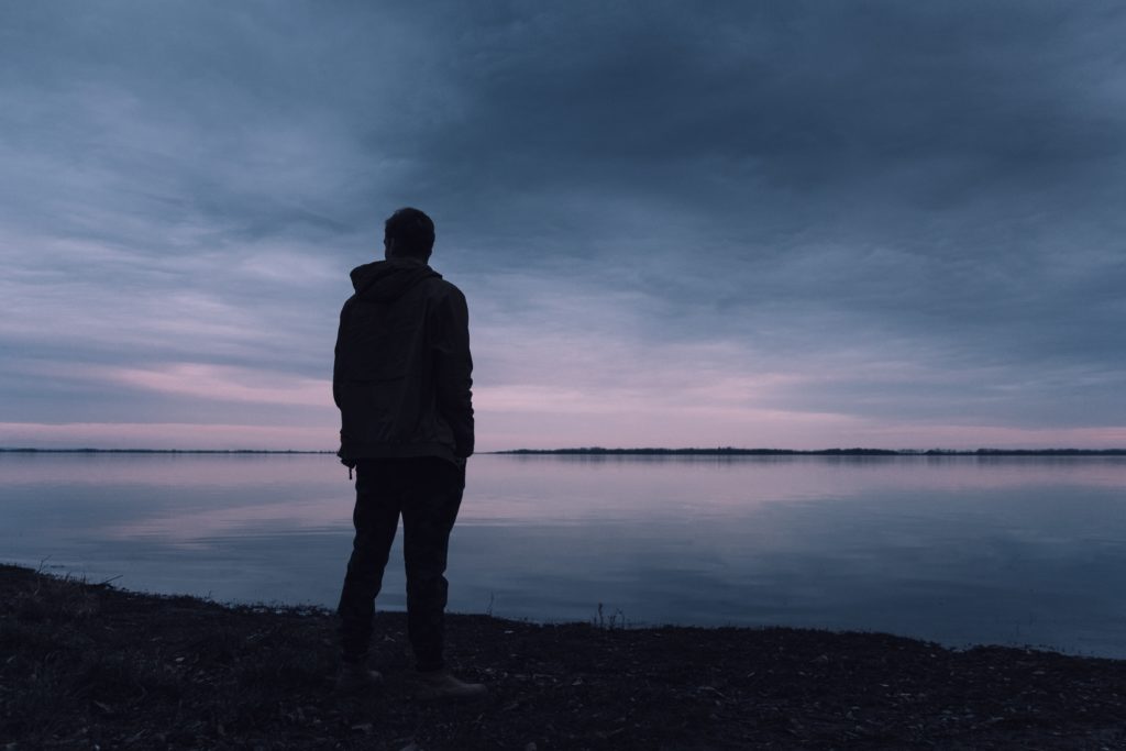 Mental Health man standing next to lake 
